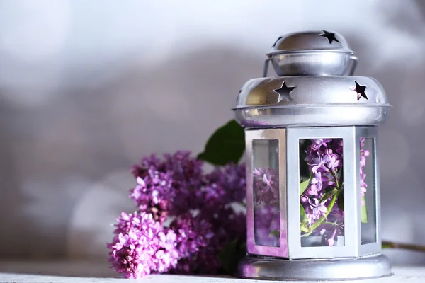 Beautiful lilac flowers in vase, on color wooden table, on dark background — Stock Photo, Image