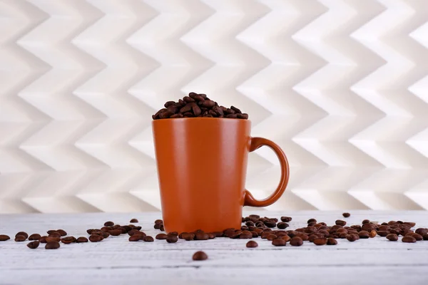 Copo cheio de grãos de café no fundo claro — Fotografia de Stock
