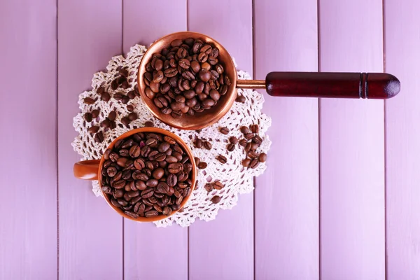 Puchar i pełne ziarna kawy na jasnym tle cezve — Zdjęcie stockowe