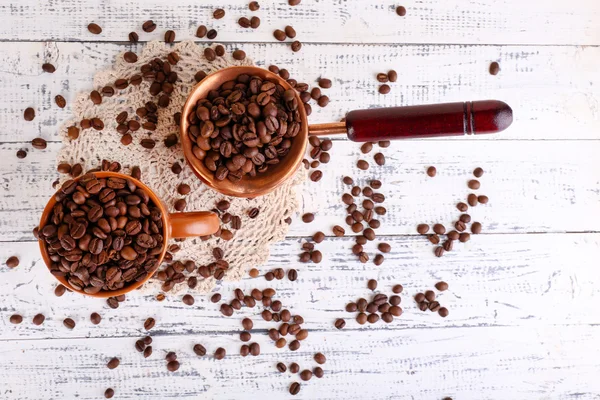 Cup  and cezve full of coffee beans on light background — Stock Photo, Image