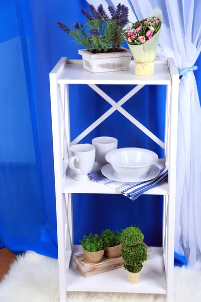Schöne weiße Regale mit Geschirr und Dekor auf farbigem Hintergrund — Stockfoto