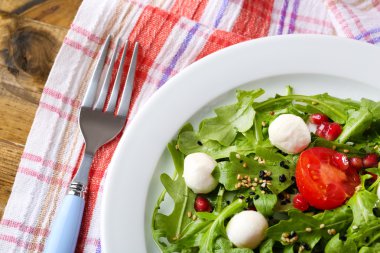 roka, domates, peynir mozzarella toplar ve ahşap zemin üzerinde plaka üzerinde susam ile yapılan yeşil salata
