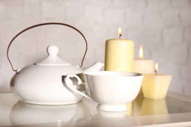 Çay Kupası ve çaydanlık ve masada açık renkli mum ile kompozisyon