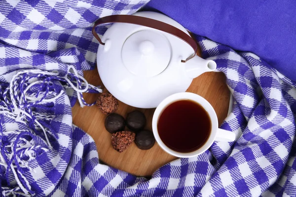 Cup and teapot with candies on wooden stand on bed close up — Stock Photo, Image