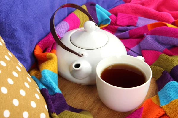 Tasse und Teekanne auf Holzständer und Schal auf dem Bett aus nächster Nähe — Stockfoto