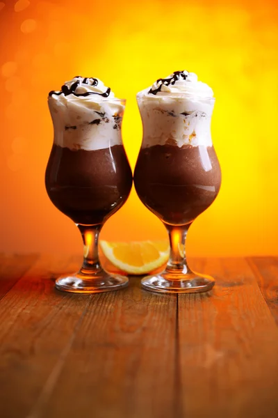 Gustoso dessert con cioccolato, crema e salsa d'arancia, su tavolo di legno, su sfondo luci — Foto Stock