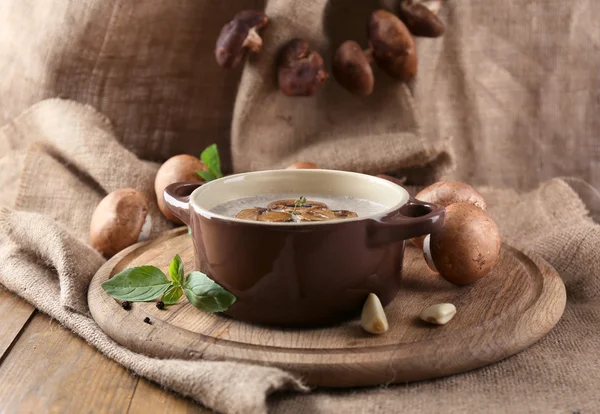 Composición con sopa de champiñones en olla, champiñones frescos y secos, sobre mesa de madera, sobre fondo de saco — Foto de Stock