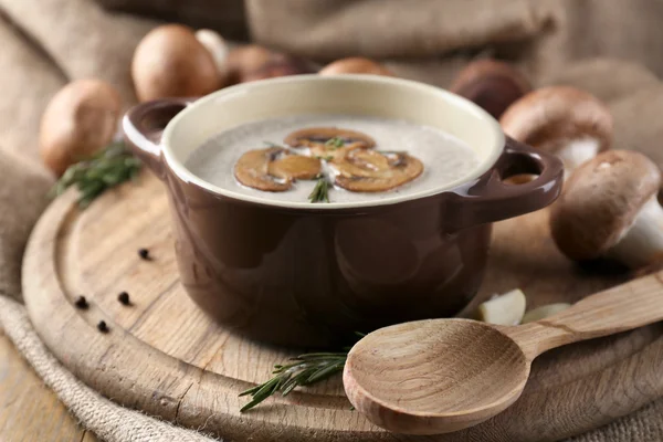 Composition with mushroom soup in pot, fresh and dried mushrooms, on wooden table, on sackcloth background — Stock Photo, Image