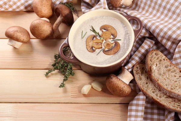 Mushroom soup in pot, on napkin,  on wooden background — Stock Photo, Image