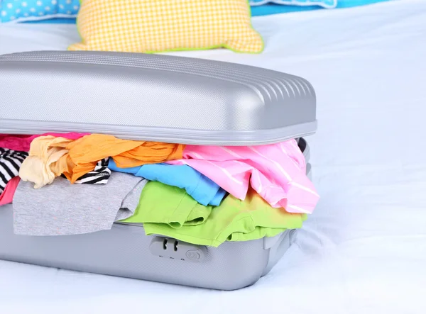 Šedý kufr s oblečením na posteli detail — Stock fotografie
