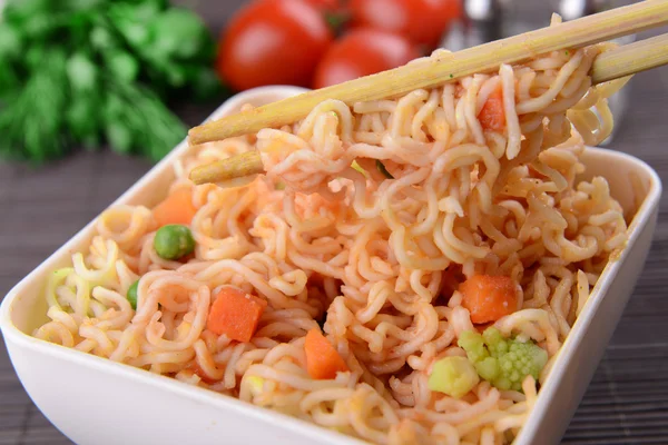 Νόστιμο στιγμιαία noodles με λαχανικά σε μπολ σε κοντινό πλάνο του πίνακα — Φωτογραφία Αρχείου