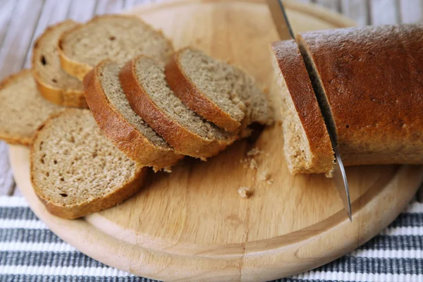 Mani femminili taglio del pane su tavola di legno, primo piano — Foto Stock