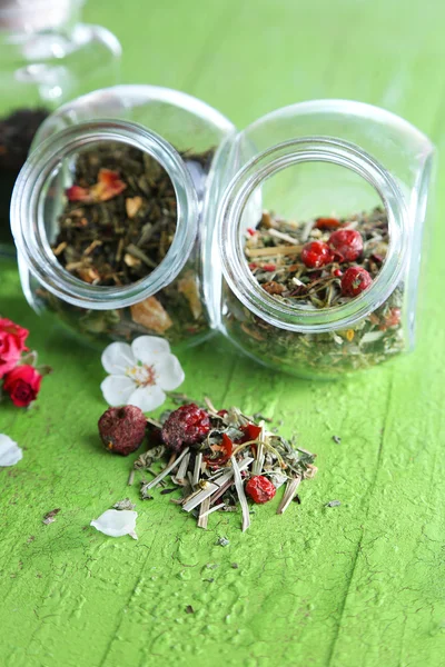 Sortimento de ervas e chá em frascos de vidro no fundo de madeira — Fotografia de Stock