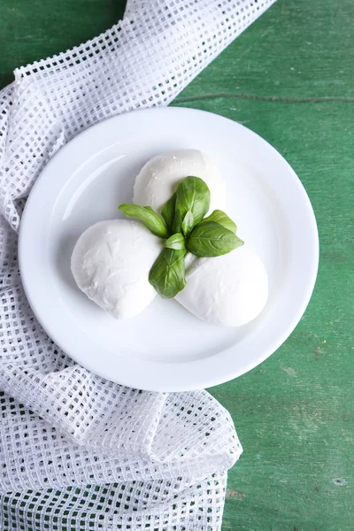 Schmackhafter Mozzarella-Käse mit Basilikum auf Teller auf Holzgrund — Stockfoto