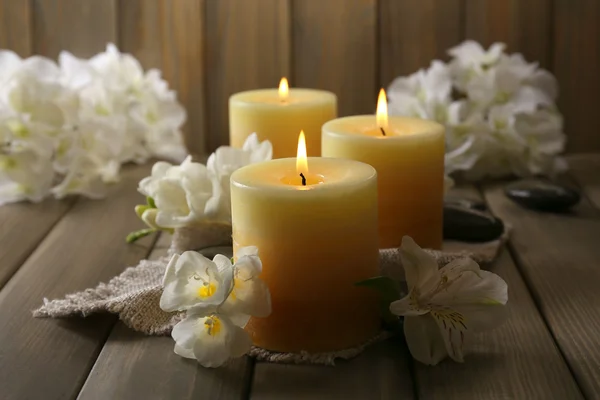 Hermosas velas con flores sobre fondo de madera — Foto de Stock