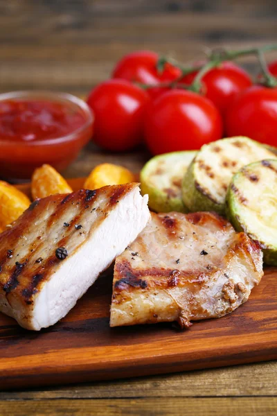 Bistecca alla griglia, verdure alla griglia e pezzi di patate fritte su tavola di legno sullo sfondo del tavolo — Foto Stock