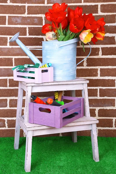 Composition of colorful tulips in watering can and equipment for gardening on bright background — Stock Photo, Image