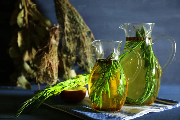 Essential Oil with rosemary in glass jugs, on wooden background — Stock Photo, Image