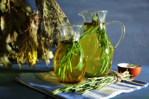 Olio essenziale con rosmarino in brocche di vetro, su fondo di legno — Foto Stock