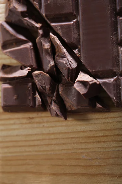 Chopped bar of chocolate on wooden background — Stock Photo, Image