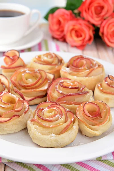 Вкусное слоеное тесто с розами в форме яблока на тарелке на столе крупным планом — стоковое фото