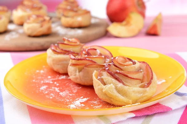 Tasty bladerdeeg met apple vormige rozen op plaat op tabel close-up — Stockfoto