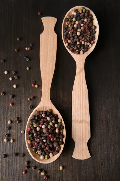 Pimienta de especias en cucharas sobre fondo de madera — Foto de Stock