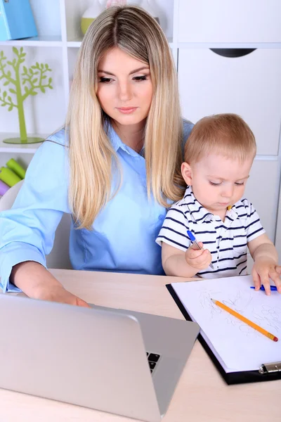 Mujer bonita con bebé trabajando en casa — Foto de Stock