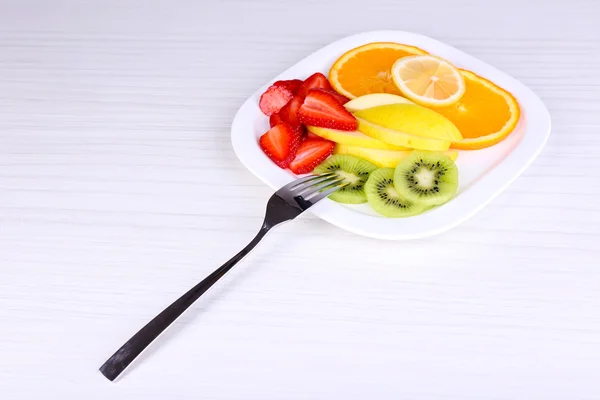 Различные нарезанные фрукты на тарелке на столе крупным планом — стоковое фото