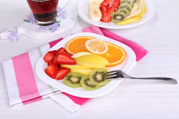 Various sliced fruits on plates on table close-up — Stock Photo, Image