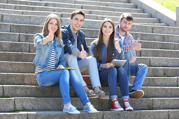 Šťastní studenti sedí na schodech v parku — Stock fotografie