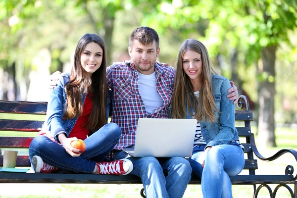 Estudiantes felices sentados en el parque — Foto de Stock