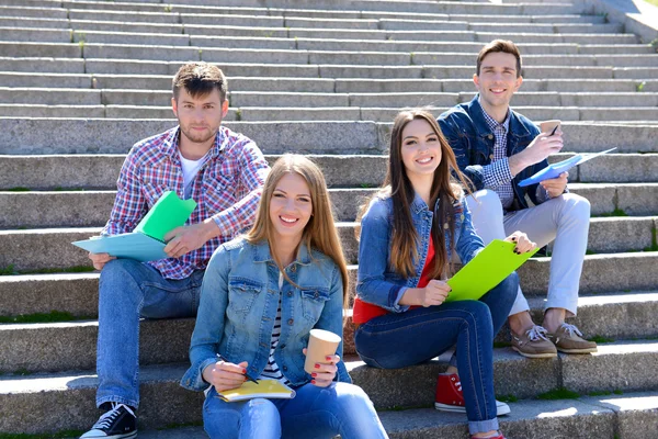 Šťastní studenti sedí na schodech v parku — Stock fotografie