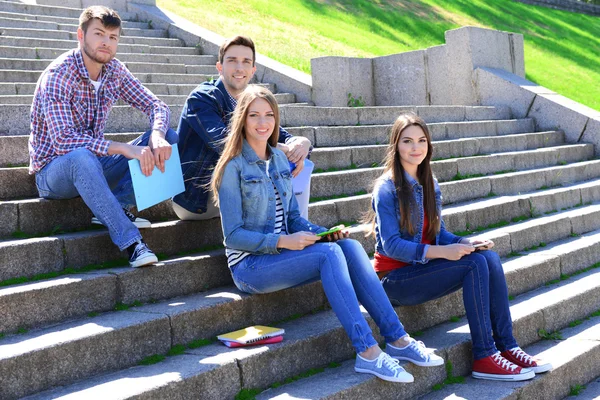 Šťastní studenti sedí na schodech v parku — Stock fotografie