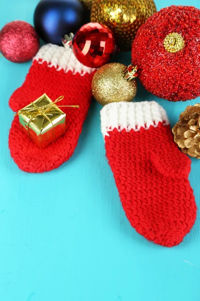 Manoplas rojas de invierno con juguetes de Navidad en mesa de madera azul —  Fotos de Stock