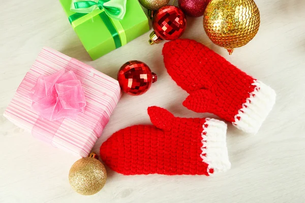 Rote Winterhandschuhe mit Weihnachtsspielzeug auf Holztisch — Stockfoto