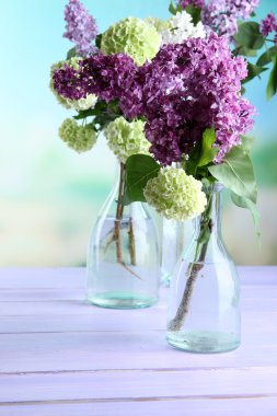 güzel bahar çiçekleri parlak zemin üzerine ahşap masa üzerinde cam şişelerde