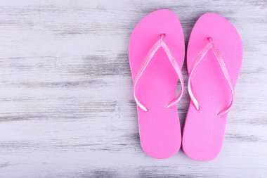 Renkli ahşap arka planda parlak parmak arası terlikler