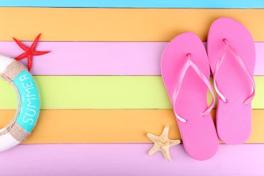 Renkli ahşap arka planda parlak parmak arası terlikler