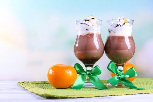 Tasty dessert with chocolate, cream and orange sauce, on napkin. on wooden table, on light background — Stock Photo, Image