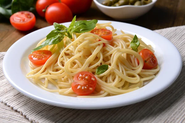 Utsökt spaghetti med tomater på tallriken på bordet närbild — Stockfoto