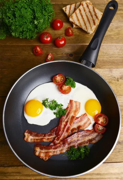 Huevos revueltos y tocino en la sartén en la mesa de cerca —  Fotos de Stock