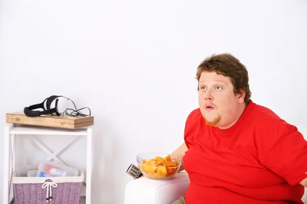 Hombre perezoso con sobrepeso sentado en el sofá y viendo la televisión — Foto de Stock