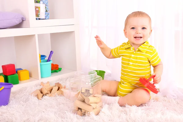 Menino bonito com blocos de brinquedo de madeira no quarto — Fotografia de Stock