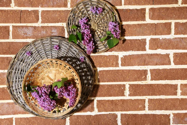 Frumoase flori de liliac în coș de răchită pe fundal de pietre de culoare — Fotografie, imagine de stoc