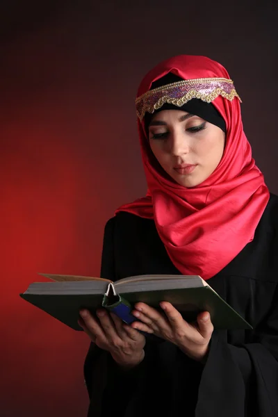 Mulher árabe muçulmana bonita leitura livro sobre fundo de cor escura — Fotografia de Stock