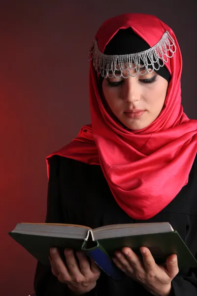 Hermosa mujer árabe musulmana leyendo libro sobre fondo de color oscuro —  Fotos de Stock