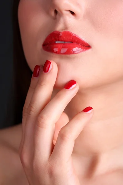 Girl with red lips and nails on dark background — Stock Photo, Image