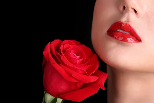 Chica con labios rojos y rosa sobre fondo oscuro —  Fotos de Stock