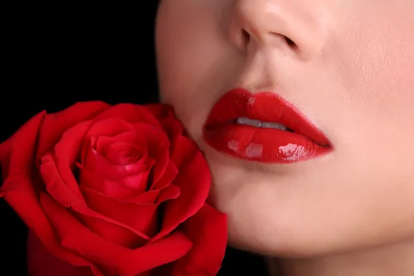 Mädchen mit roten Lippen und Rose auf dunklem Hintergrund — Stockfoto